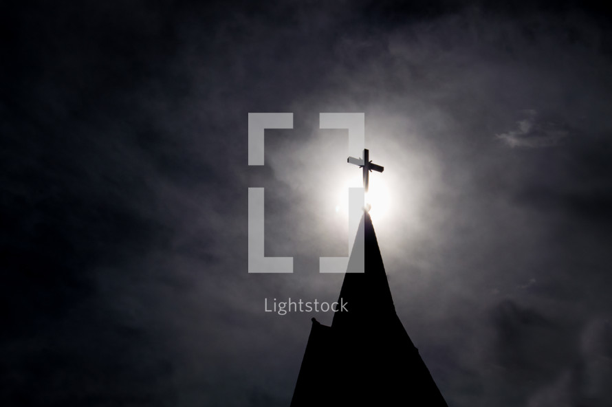 light shining on a cross on a steeple 