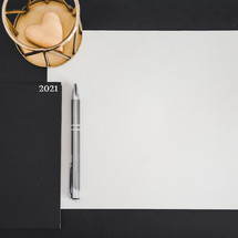 planner for 2021, blank piece of paper, and pen on a desk 