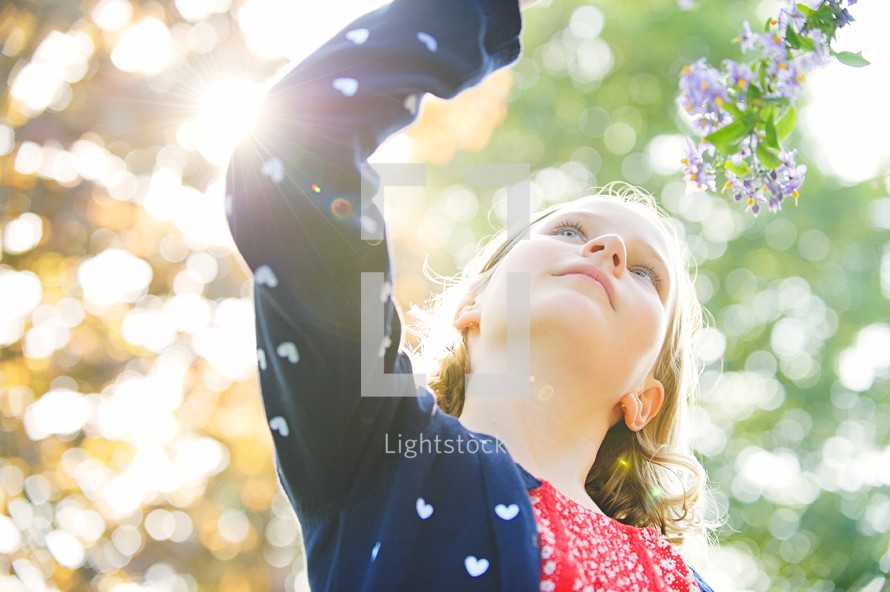 a girl smelling flowers outdoors 