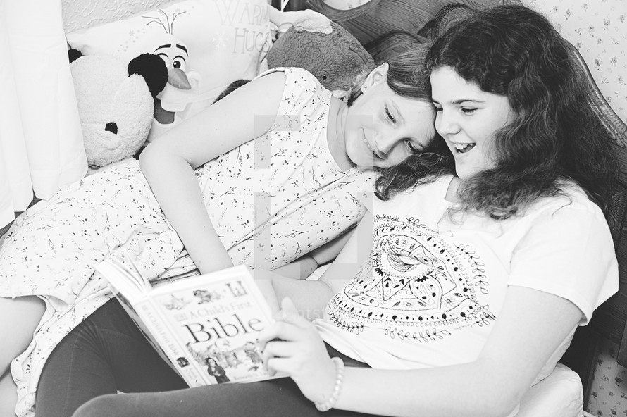 sisters reading a Bible in bed 