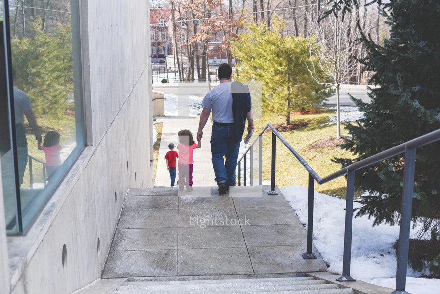 a father holding hands with his daughter walking down steps 