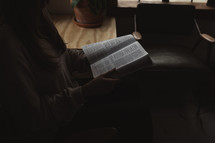 a woman reading a Bible alone at home 