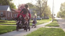 Mother and Father pushing children in stroller around neighborhood.  