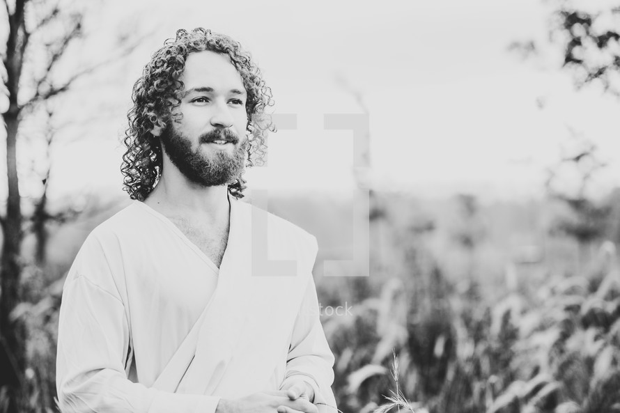 Jesus standing in a field of tall brown grasses