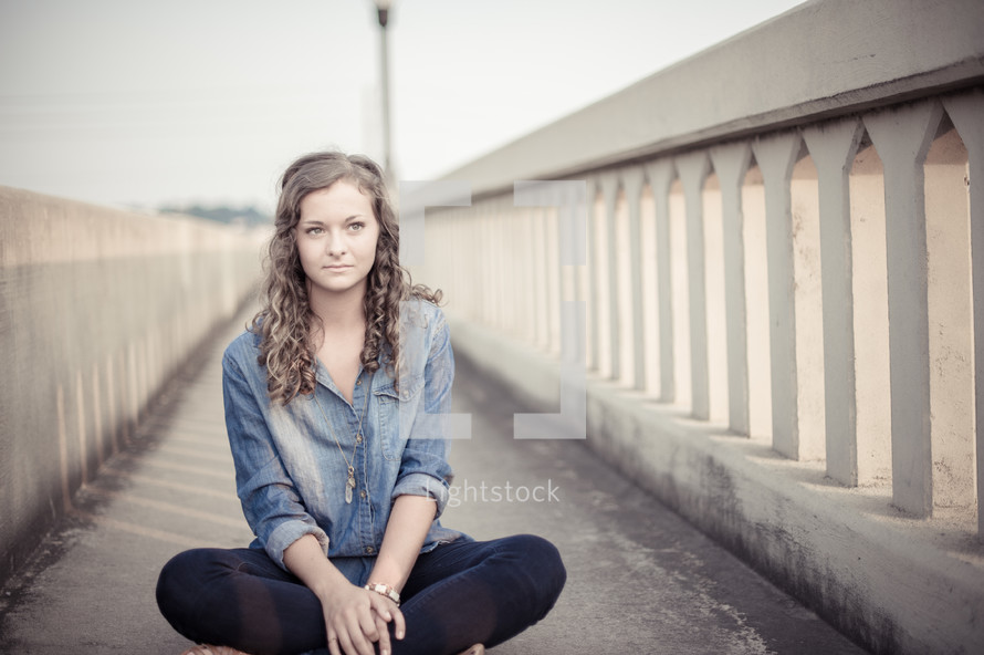 teen girl sitting on a sidewalk 