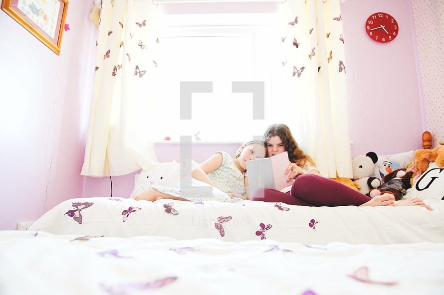 sisters reading a Bible in a bed 