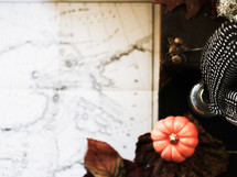 vintage map, feather, glass jar, fall leaf and mini pumpkin on a leather bound book 