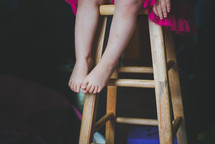 legs of a toddler girl on a stool 