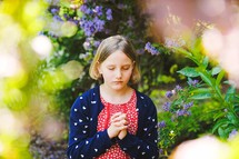 a girl in prayer standing under a flowering tree 