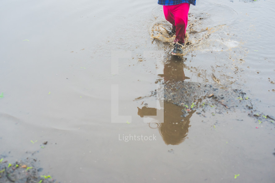 a toddler girl walking in a puddle 