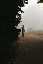 a man standing on road and fog 