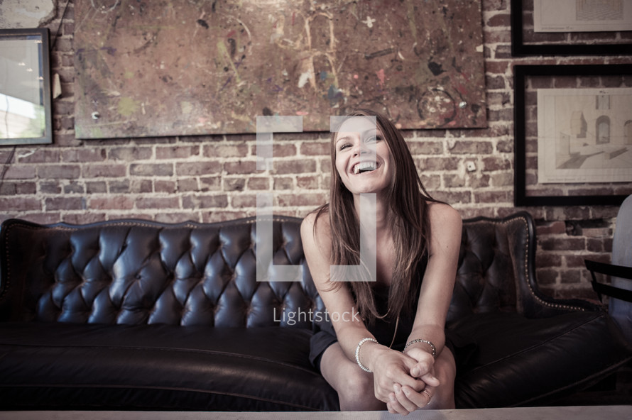 woman sitting on a leather couch smiling 