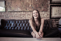 woman sitting on a leather couch smiling 