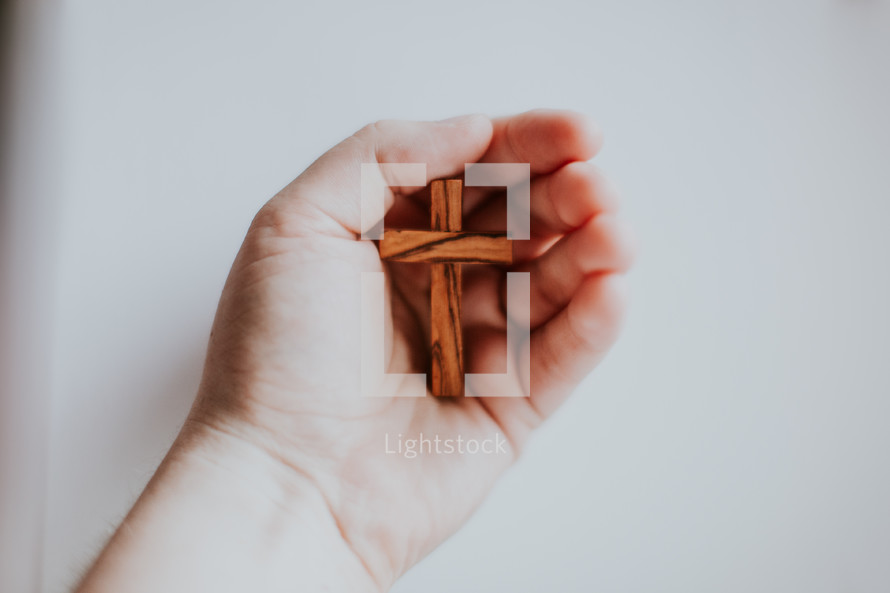 cupped hand holding a wooden cross