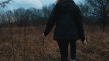 a woman walking through a field 