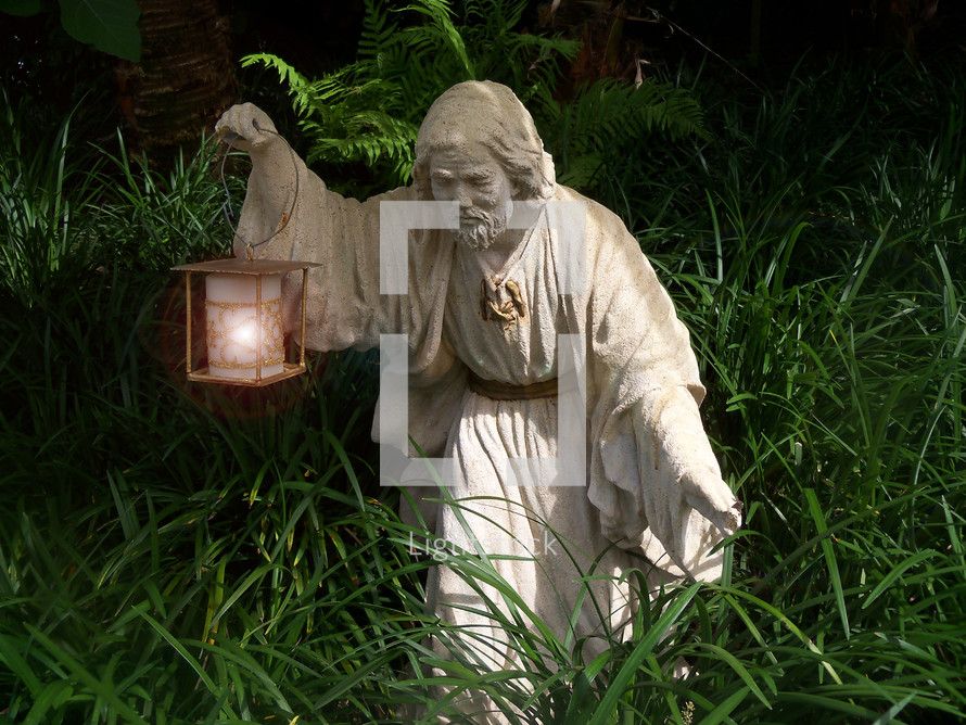 Statue of an Israelite holding a lantern to light his way through a thick path of grass and weeds as he travels by night.