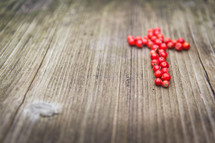a cross of red berries on a wood background 