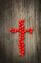 cross of red berries on a wood background 