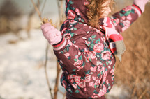 a child in a winter coat holding a stick 