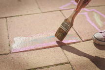a child painting a sidewalk 