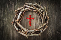 a wreath of sticks around a cross of red berries 