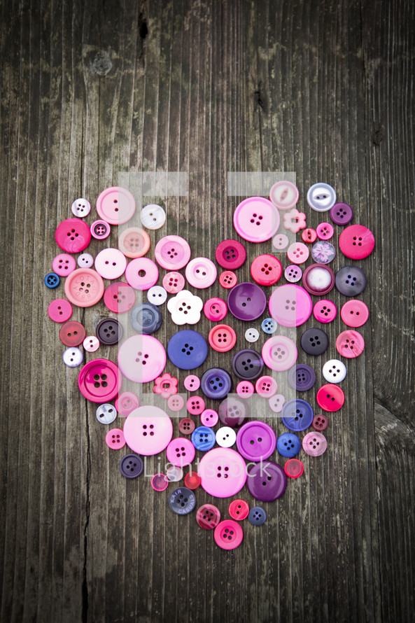 a heart of buttons on a wood background 