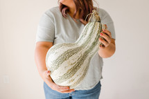 a woman holding a large gourd 