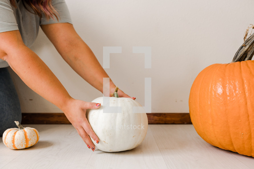 a woman decorating with pumpkins 