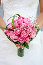 Bride holding bouquet of pink roses.