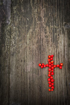 a Cross of red berries on a wood background 