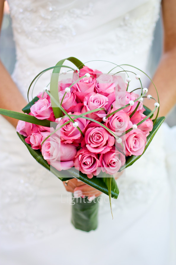 Bride holding bouquet of pink roses.