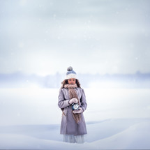 a girl standing in the snow holding an alarm clock 