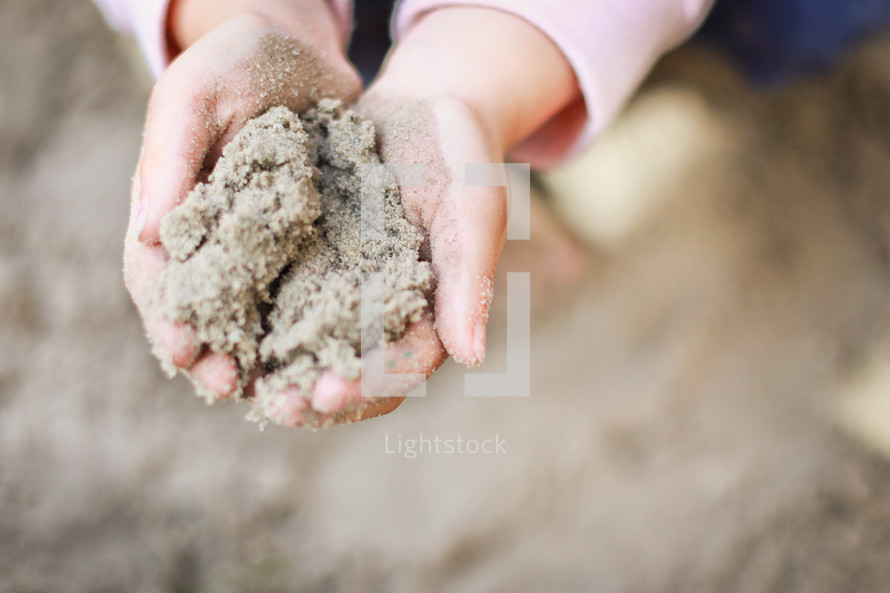 a child with hands full of sand 