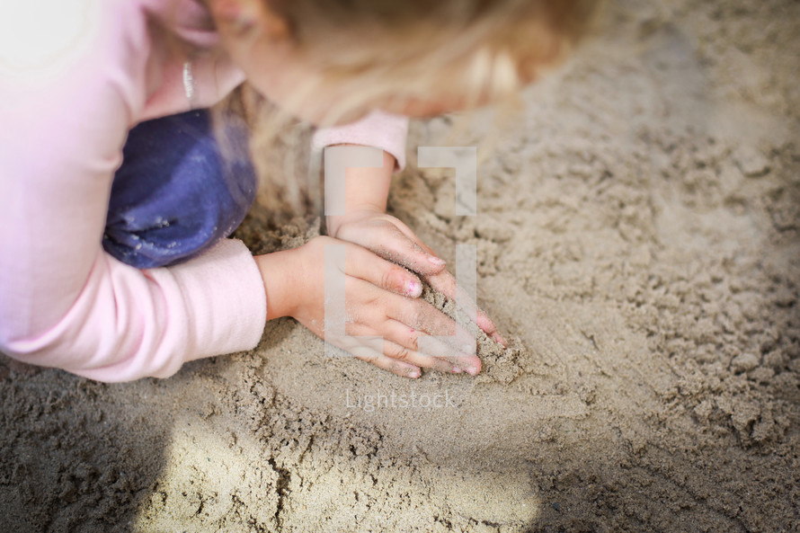 a child playing in a sand box 