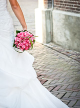 A bride holding a bridal bouquet on a brick walk.