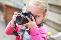 a girl child taking a picture with a camera 