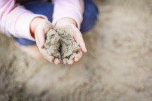 a child with hands full of sand 