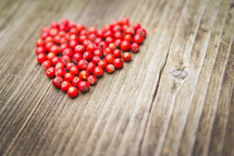 a heart of red berries on a wood background 