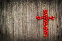 cross of red berries on a wood background 
