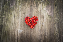 heart of red berries on a wood background