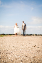 a blurry image of a bride and groom on a dirt road 