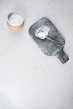 spoon of sugar and bowl on a cutting board in a kitchen 