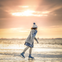 little girl ice skating on a pond 