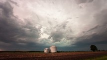 TImelapse of a thunderstorm approaching over rural farmland in the midwest.  A wall cloud forms and lightning strikes abound while a tractor scampers across the field. 