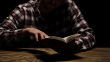 man turning the pages and reading a Bible 