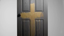 a gold cross painted on a black door 