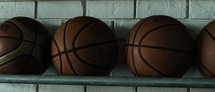 hands grabbing a basketball off a rack at a rec center
