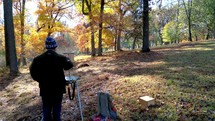 Man painting fall trees on easel
