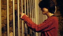 Woman gripping metal bars in distress.