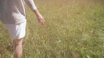 woman walking through tall grass 